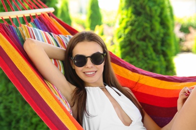 Young woman relaxing in hammock outdoors on warm summer day