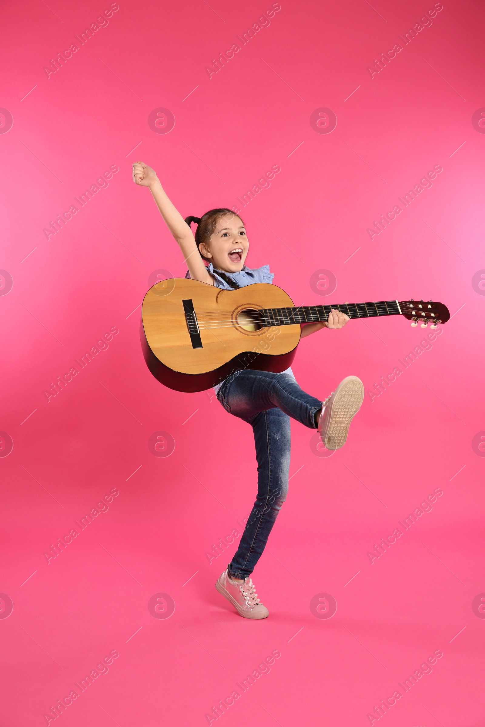 Photo of Cute little girl playing guitar on color background