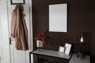 Stylish hallway interior with empty canvas on brown wall. Mockup for design