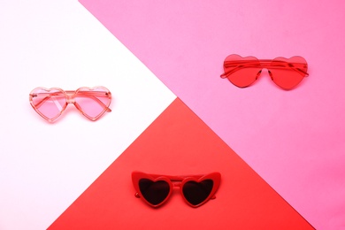 Photo of Flat lay composition with heart shaped sunglasses on color background