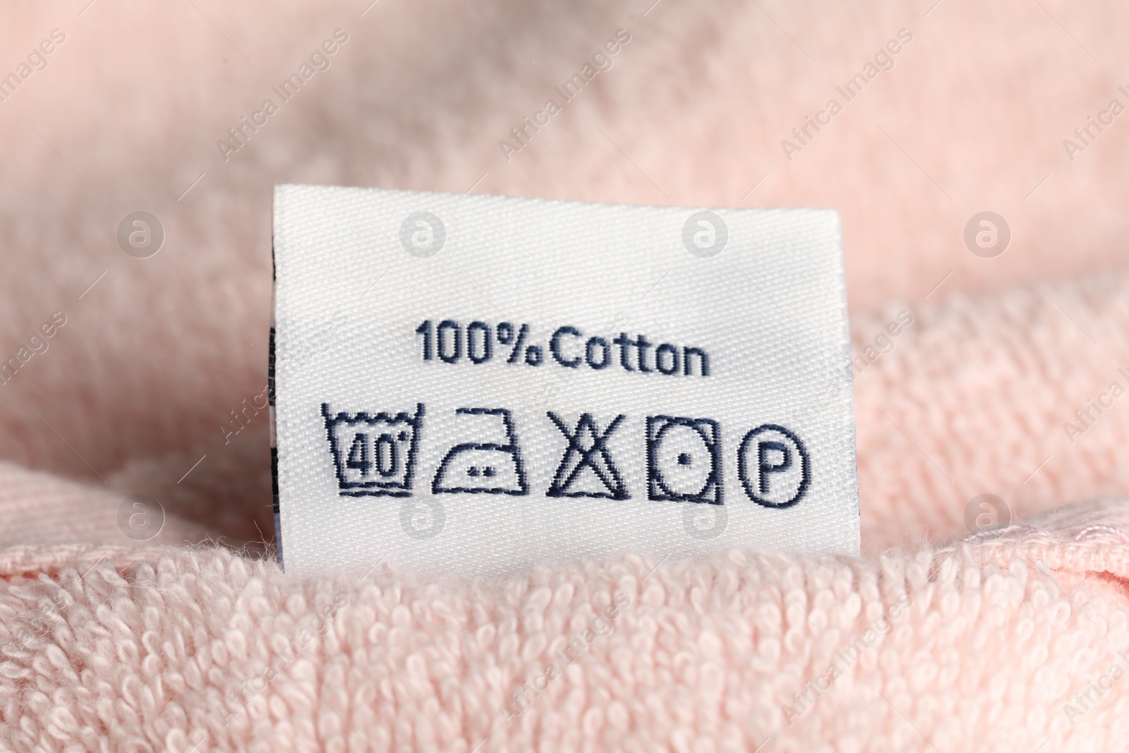 Photo of Clothing label on pink fluffy towel, closeup