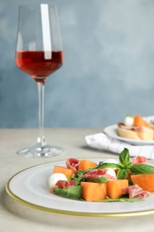 Photo of Fresh melon with prosciutto, mozzarella and basil on table