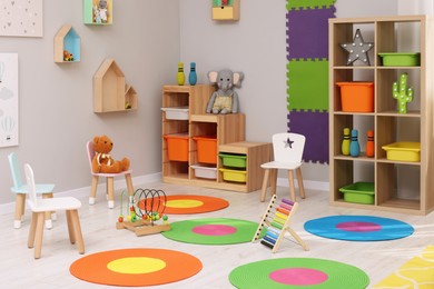 Photo of Child`s playroom with different toys and furniture. Cozy kindergarten interior