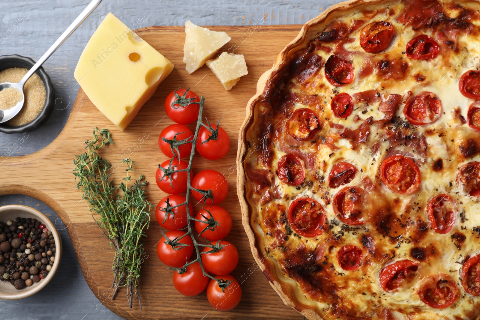 Photo of Delicious homemade prosciutto quiche and ingredients on table, flat lay