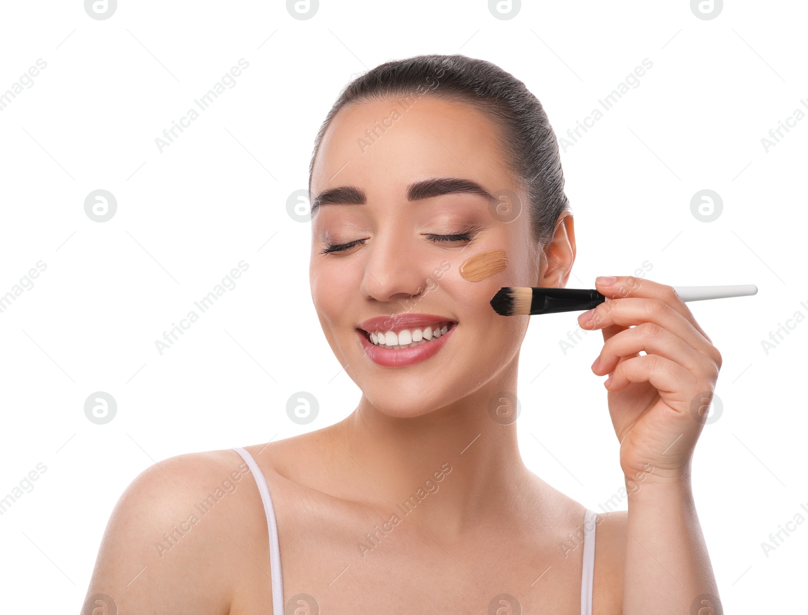 Photo of Woman applying foundation on face with brush against white background