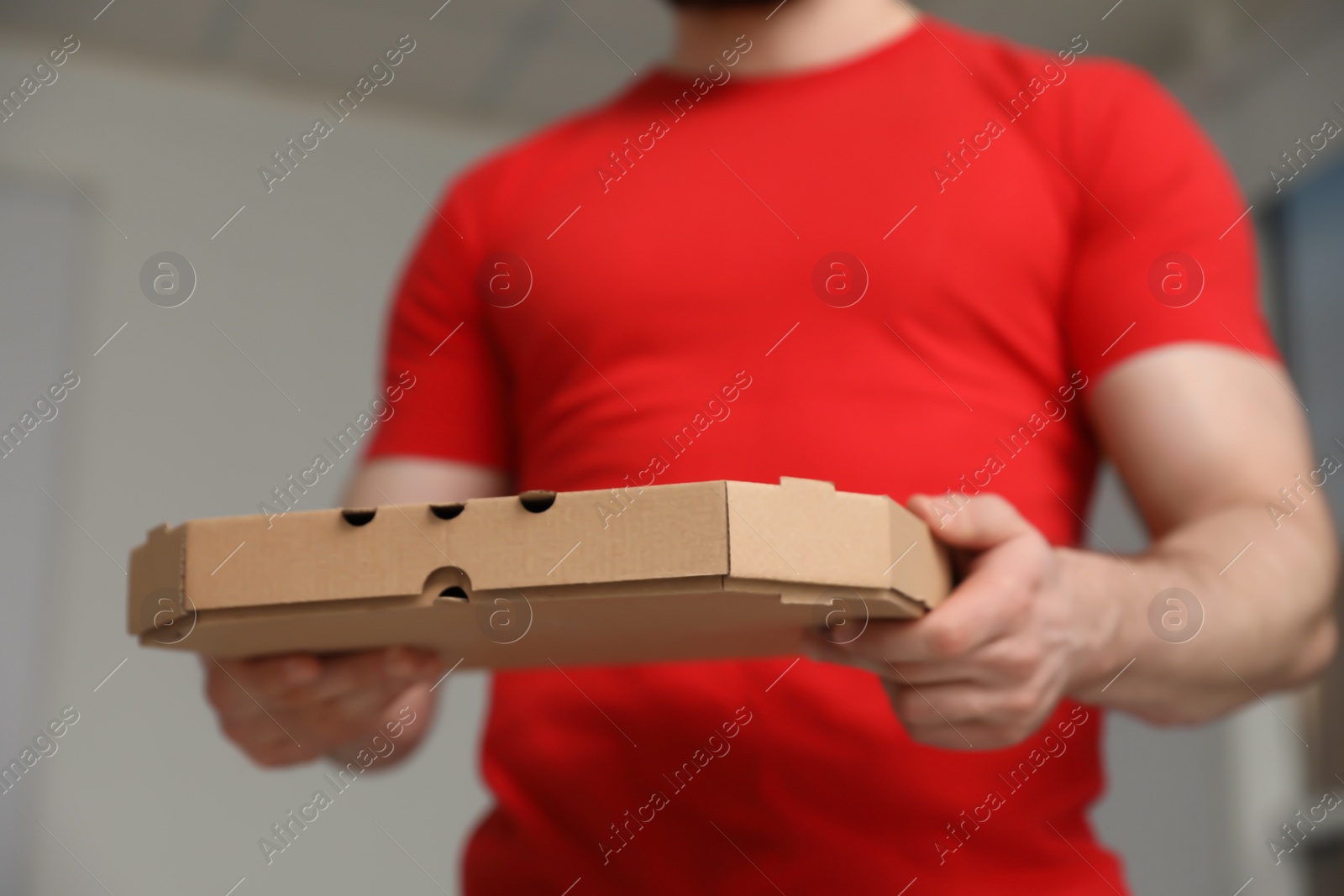 Photo of Courier with pizza box on blurred background, closeup