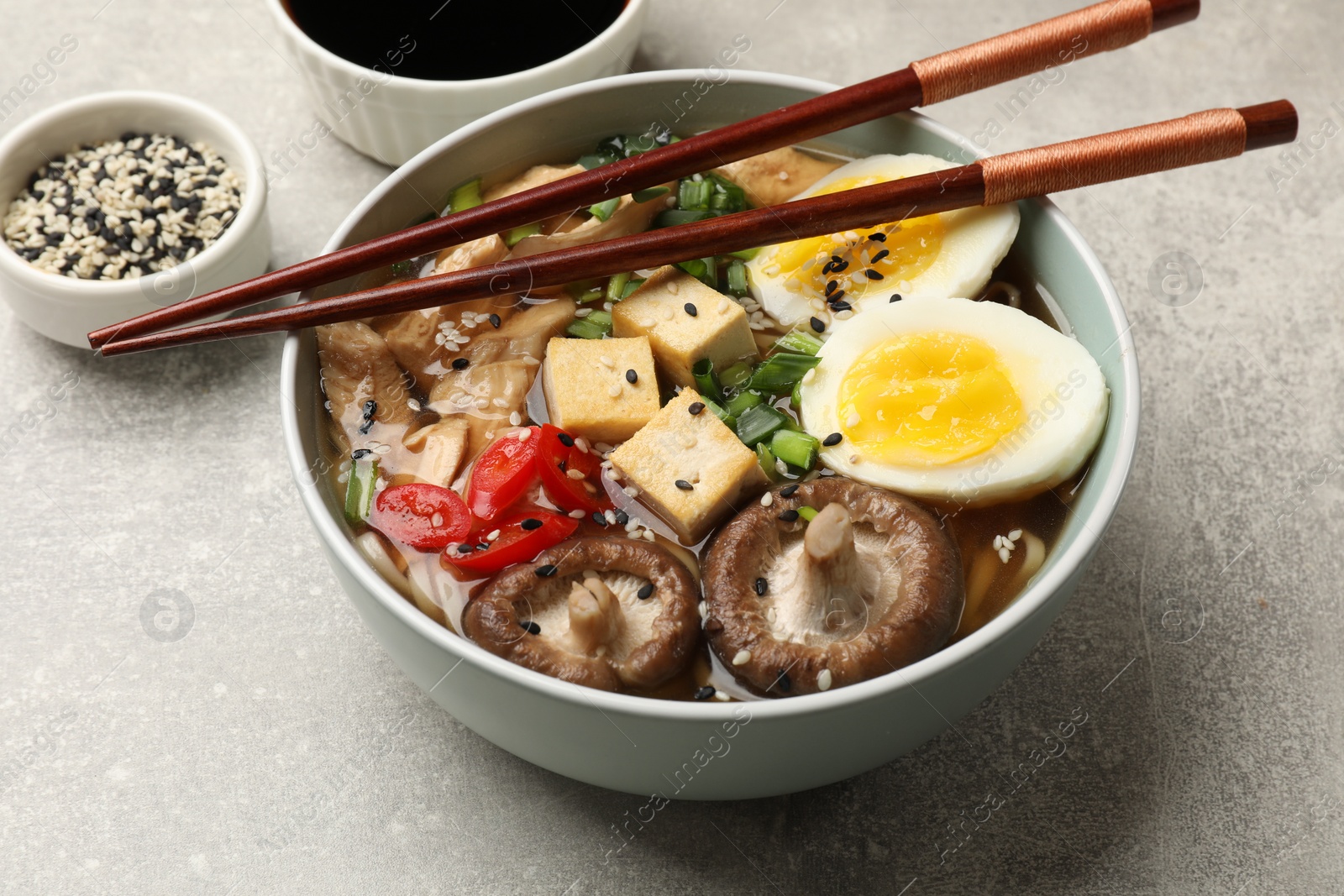 Photo of Delicious ramen served on grey table, closeup. Noodle soup