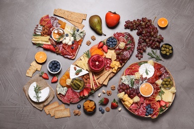 Photo of Wooden plates with different delicious snacks on grey table, flat lay