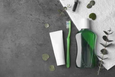 Photo of Fresh mouthwash in bottle, toothbrush, toothpaste and dental floss on dark textured table, flat lay. Space for text