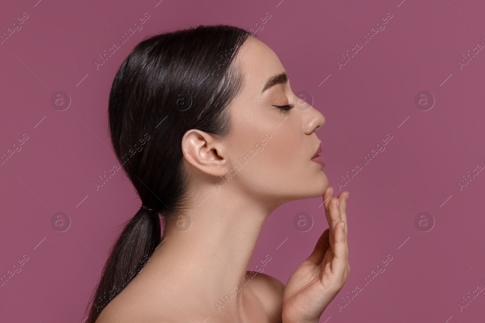Photo of Portrait of beautiful young woman with perfect makeup on dark pink background