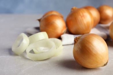 Ripe onions and rings on grey table, space for text