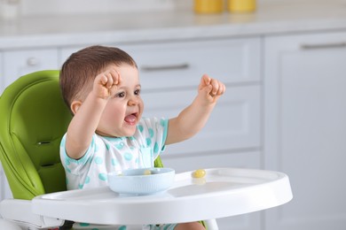 Photo of Cute little baby eating healthy food in high chair at home, space for text