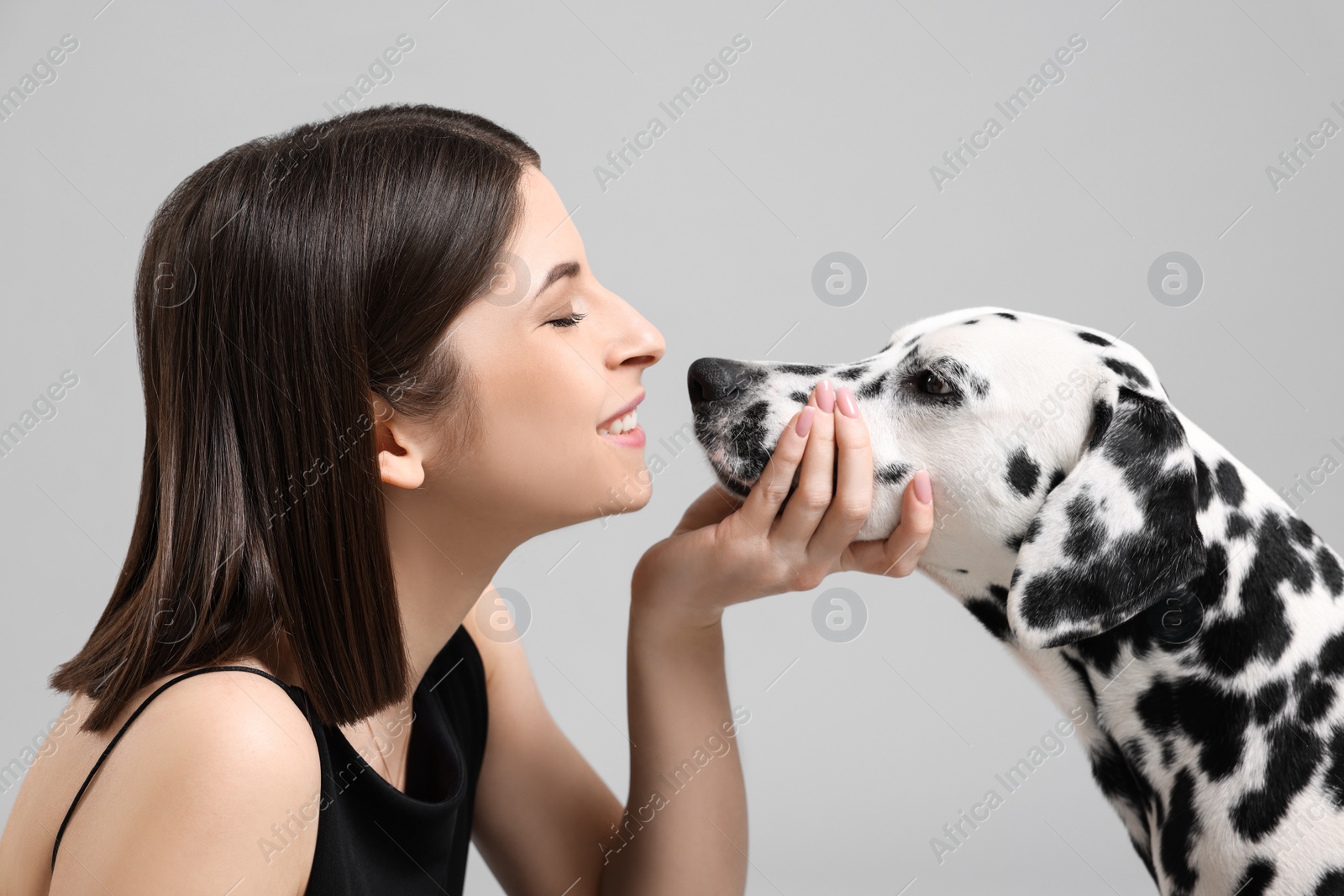 Photo of Beautiful woman with her adorable Dalmatian dog on light grey background. Lovely pet