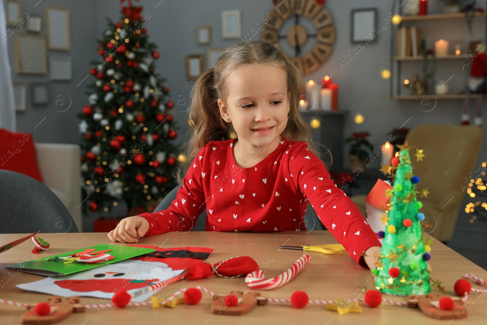 Photo of Cute little child with beautiful Christmas greeting cards and decor at home