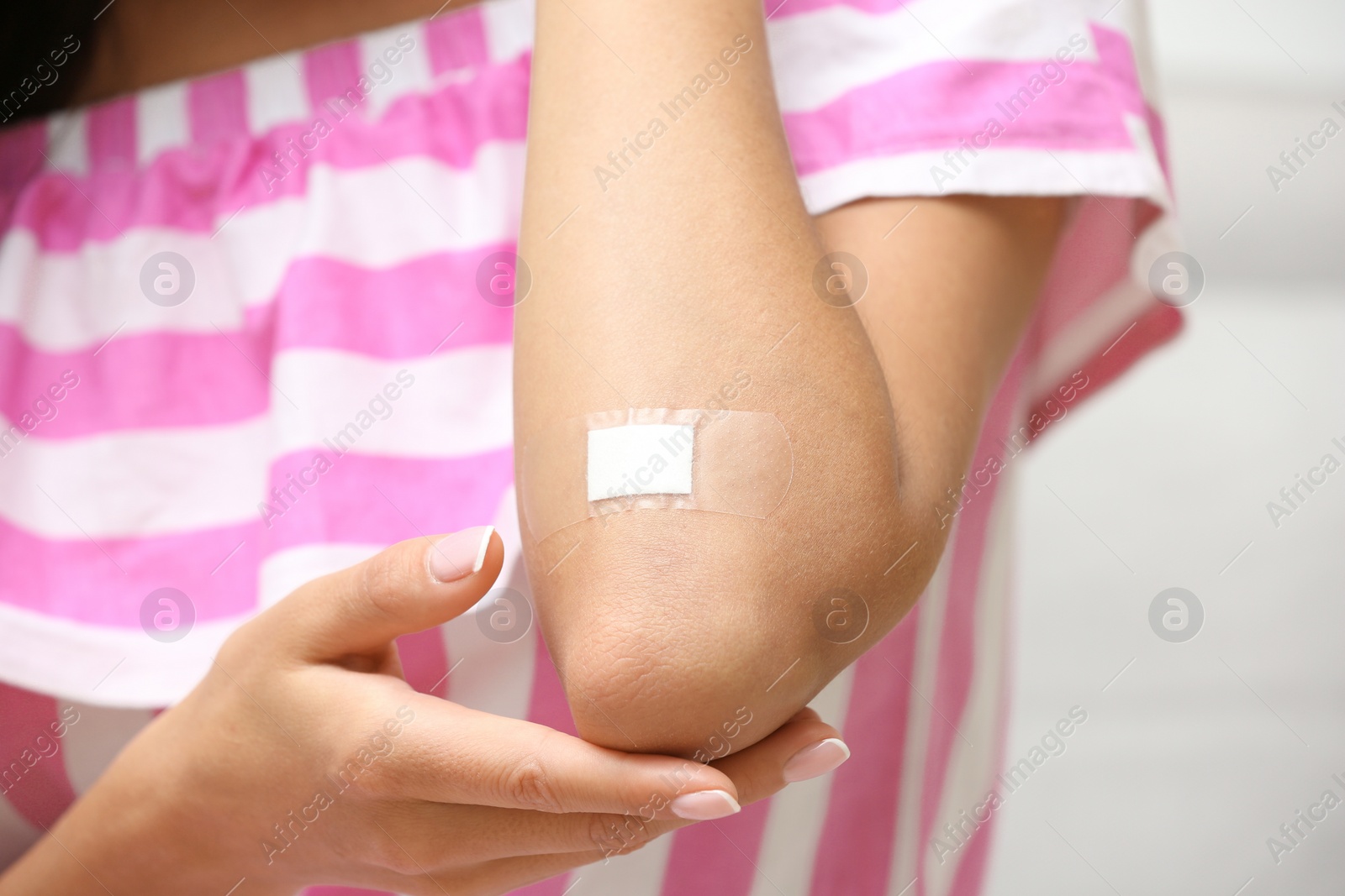 Photo of Woman with adhesive bandage on elbow against light background, closeup