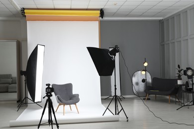 White photo background, armchair and professional lighting equipment in studio