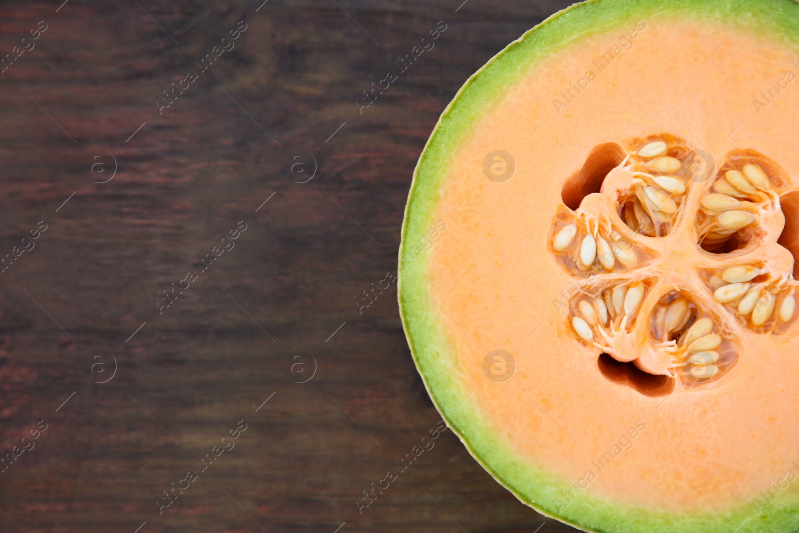 Photo of Half of fresh ripe melon on wooden table, top view. Space for text