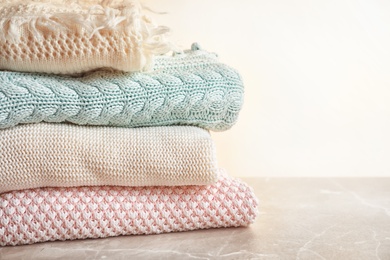 Photo of Stack of warm knitted clothes on table