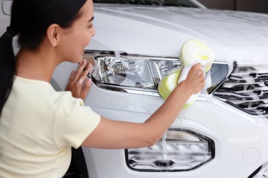 Photo of Young woman washing car with soapy sponge