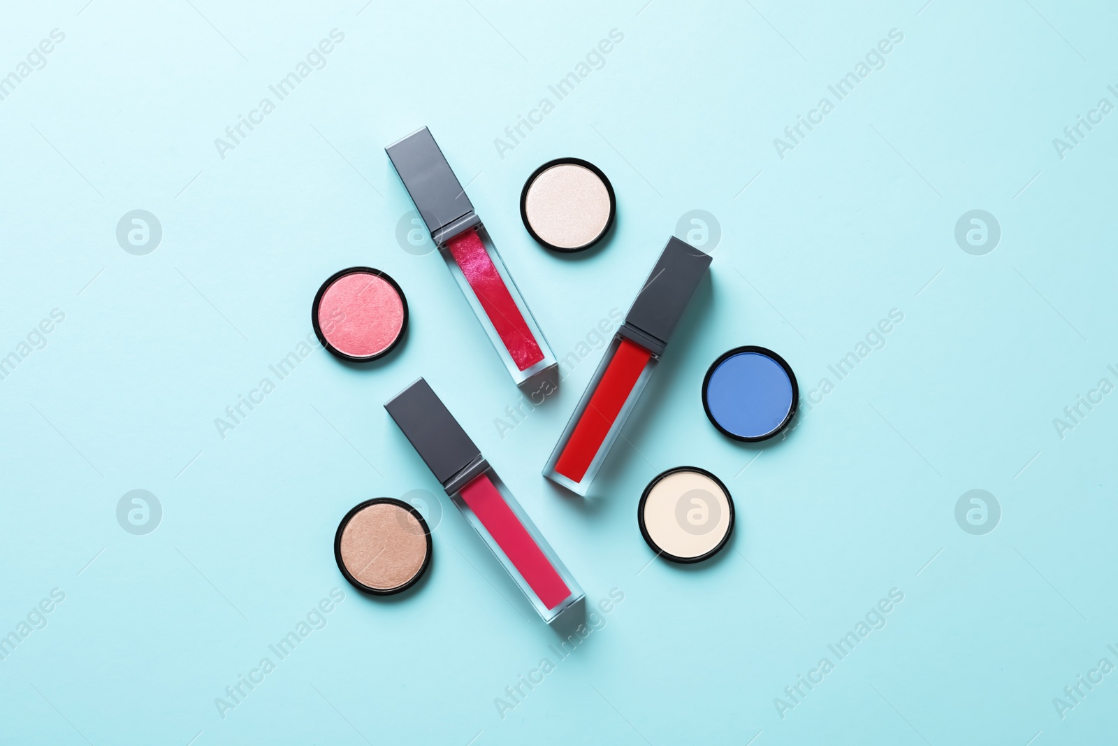 Photo of Composition of lipsticks and eyeshadows on color background, flat lay