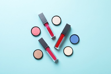 Photo of Composition of lipsticks and eyeshadows on color background, flat lay