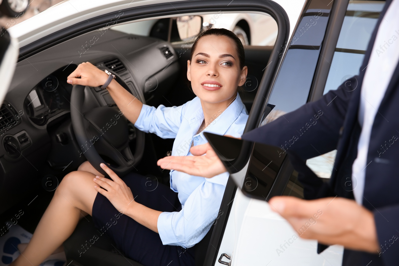 Photo of Salesman consulting young woman in auto at car dealership