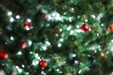 Photo of Blurred view of Christmas tree with bright string lights and ornaments, closeup. Bokeh effect