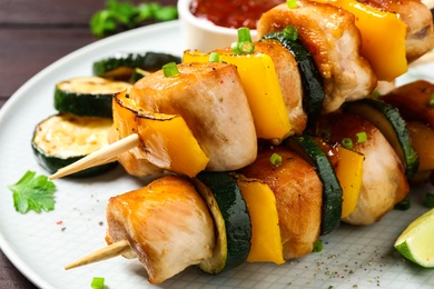 Photo of Delicious chicken shish kebabs with vegetables on plate, closeup