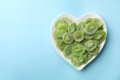 Plate of dried kiwi on color background, top view with space for text. Tasty and healthy fruit