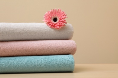 Photo of Stack of fresh towels with flower on table. Space for text