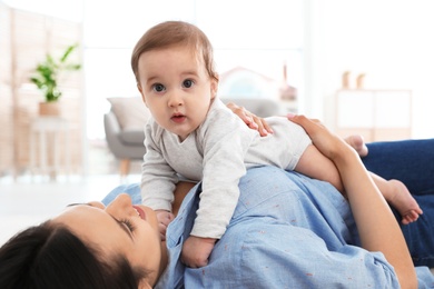 Photo of Happy young mother playing with baby on floor at home