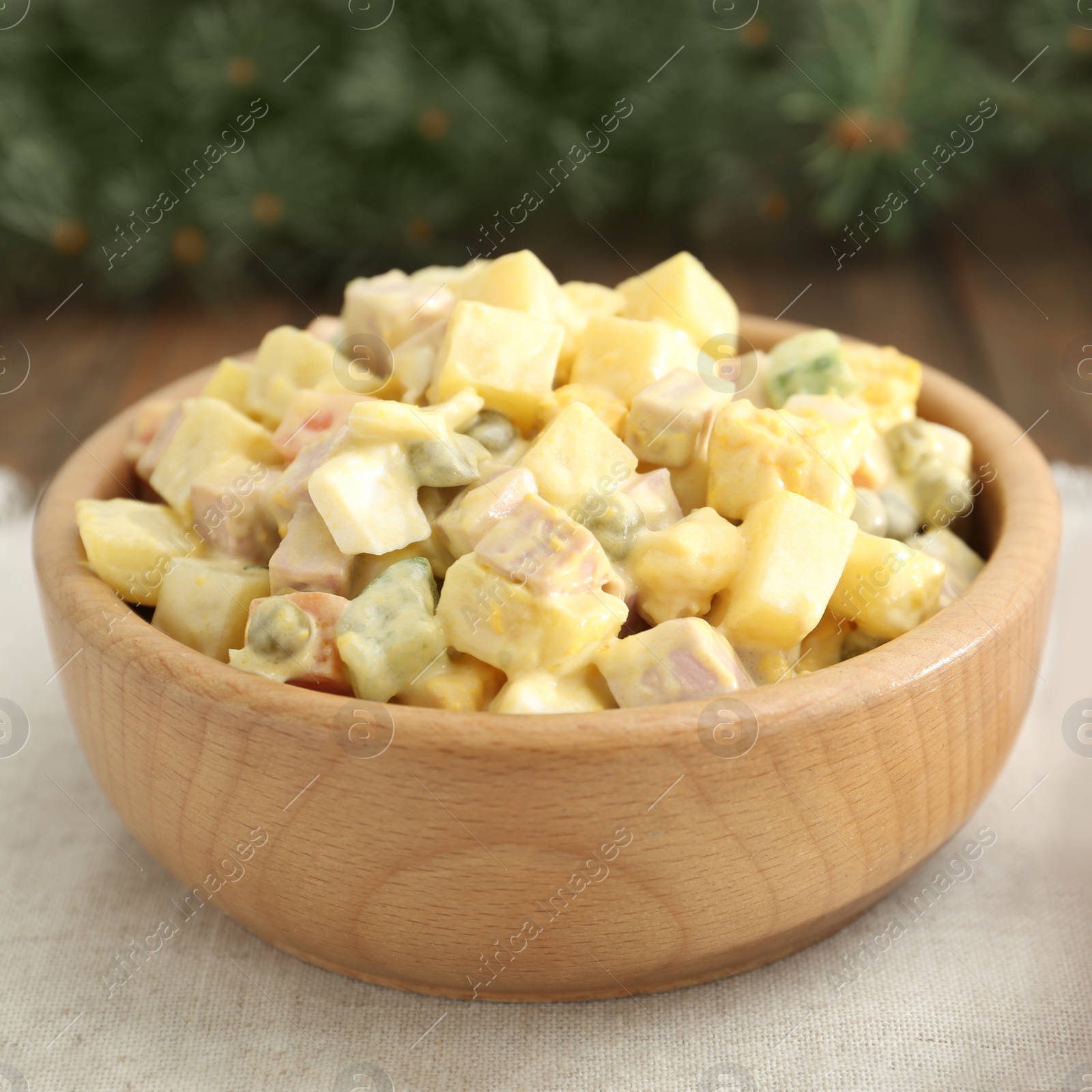 Photo of Fresh Russian salad Olivier in wooden bowl on table, closeup