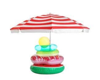 Open striped beach umbrella with different inflatable toys on white background