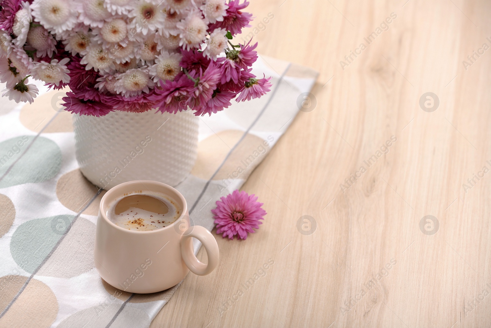 Photo of Cup of hot coffee and beautiful bouquet on wooden table. Space for text