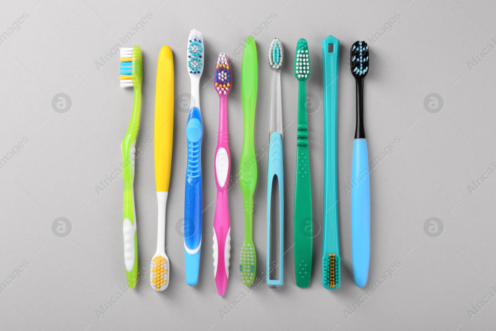 Photo of Many different toothbrushes on light background, flat lay