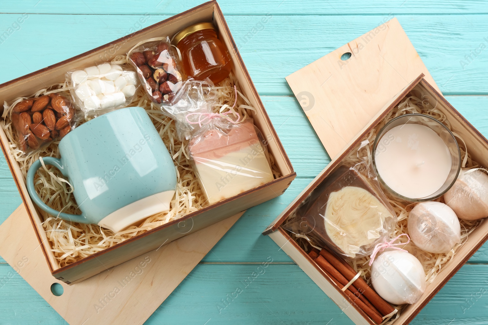 Photo of Boxes with stylish craft gift sets on light blue wooden table, flat lay