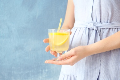 Photo of Young woman holding glass with lemon cocktail against color background