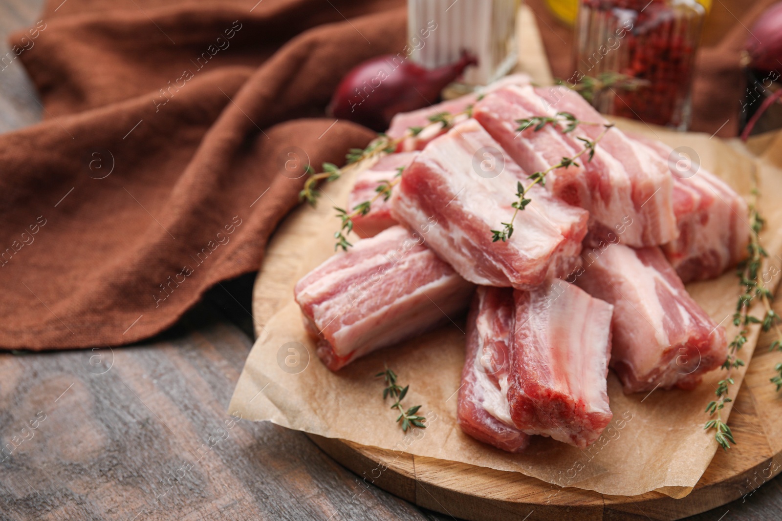 Photo of Cut raw pork ribs with thyme on wooden table, closeup. Space for text