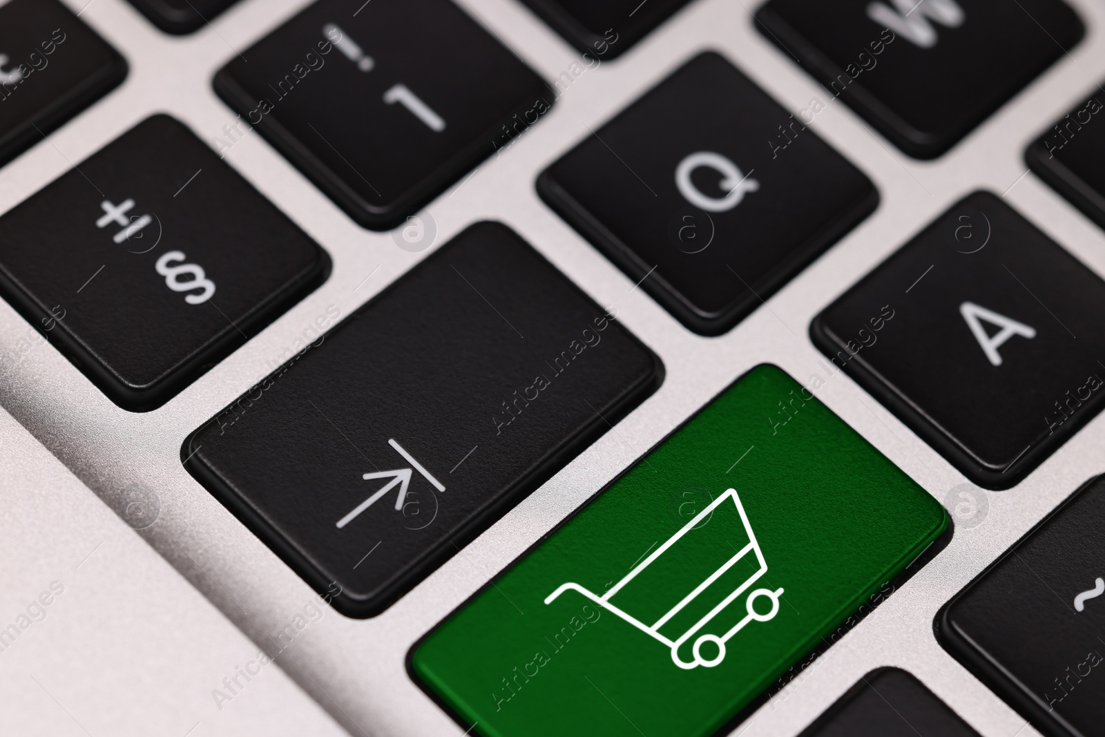 Image of Internet store. Green button with shopping cart on computer keyboard, closeup