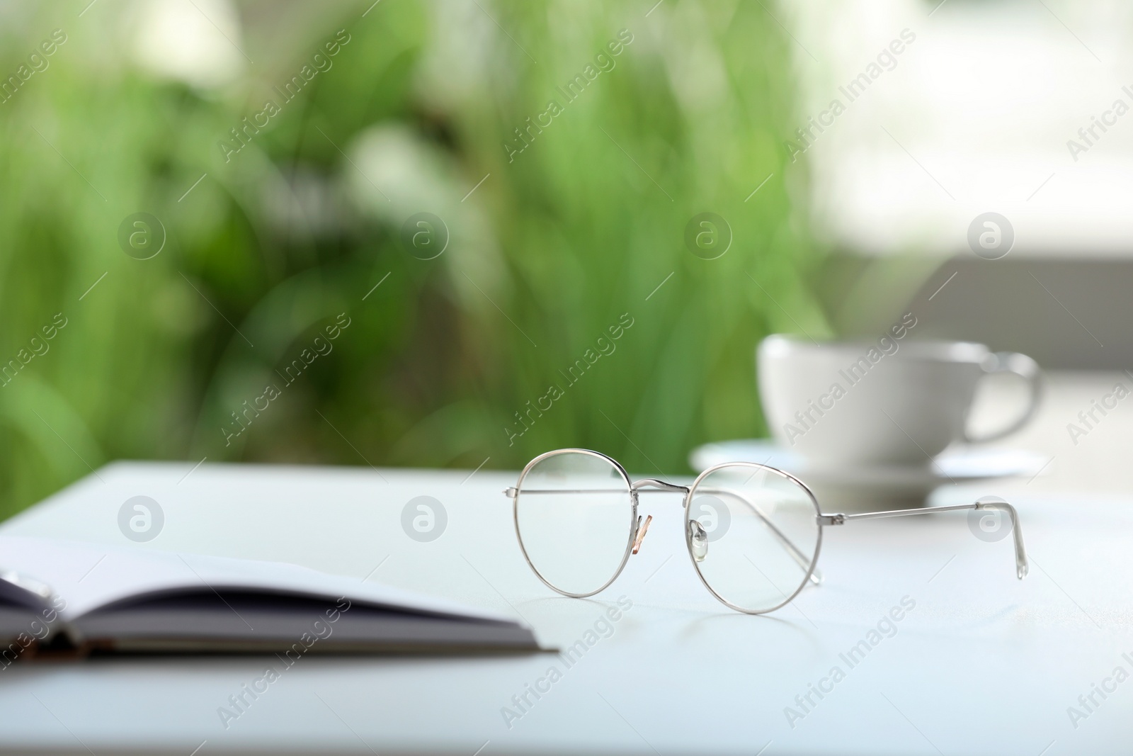 Photo of Stylish glasses and notebook on white table indoors