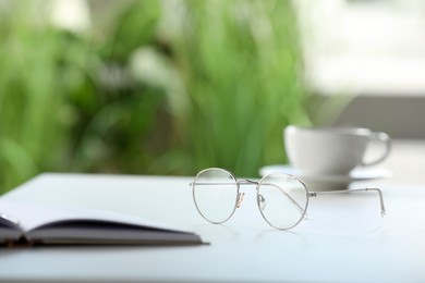 Stylish glasses and notebook on white table indoors