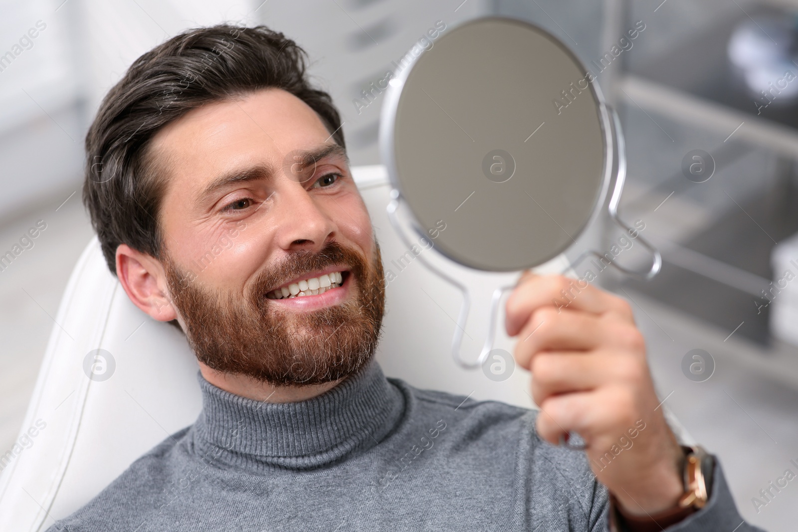 Photo of Man looking at his new dental implants in mirror indoors