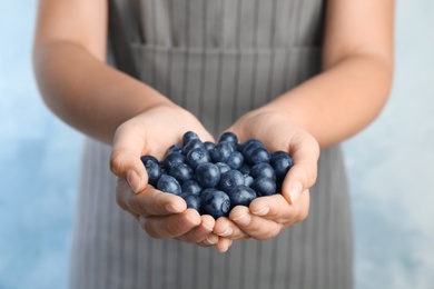 Photo of Young woman holding tasty ripe blueberries, closeup