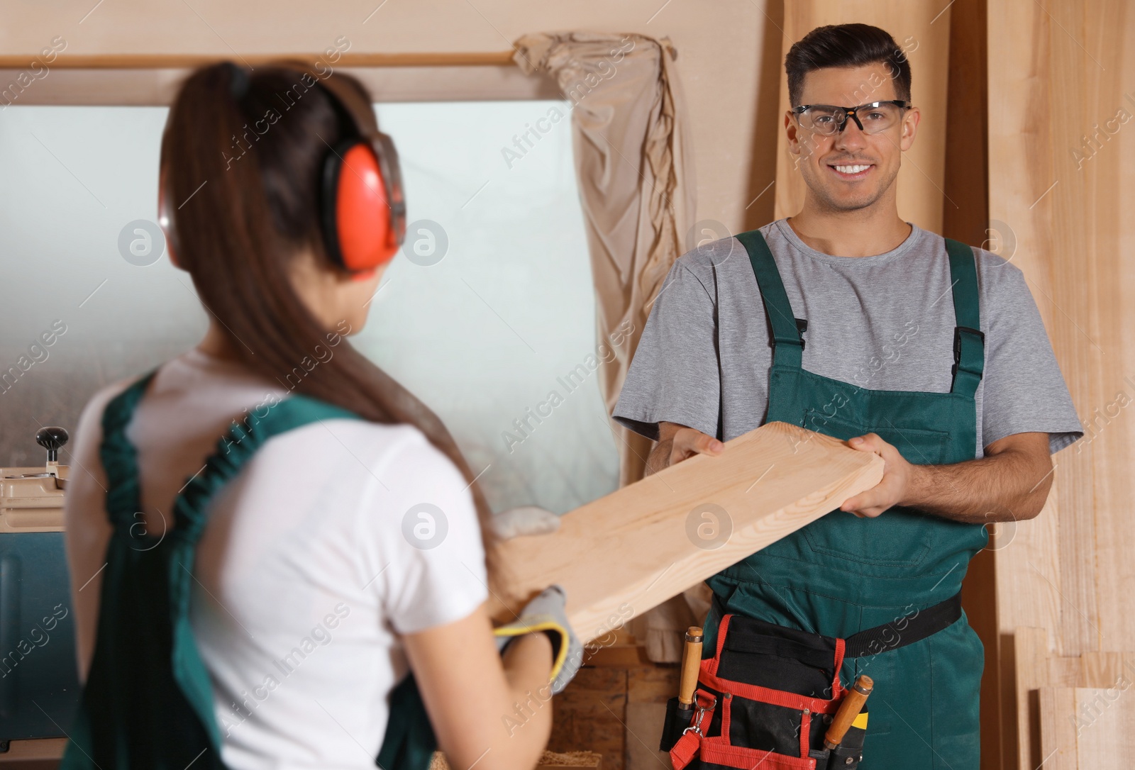 Photo of Professional carpenters with wooden plank in workshop