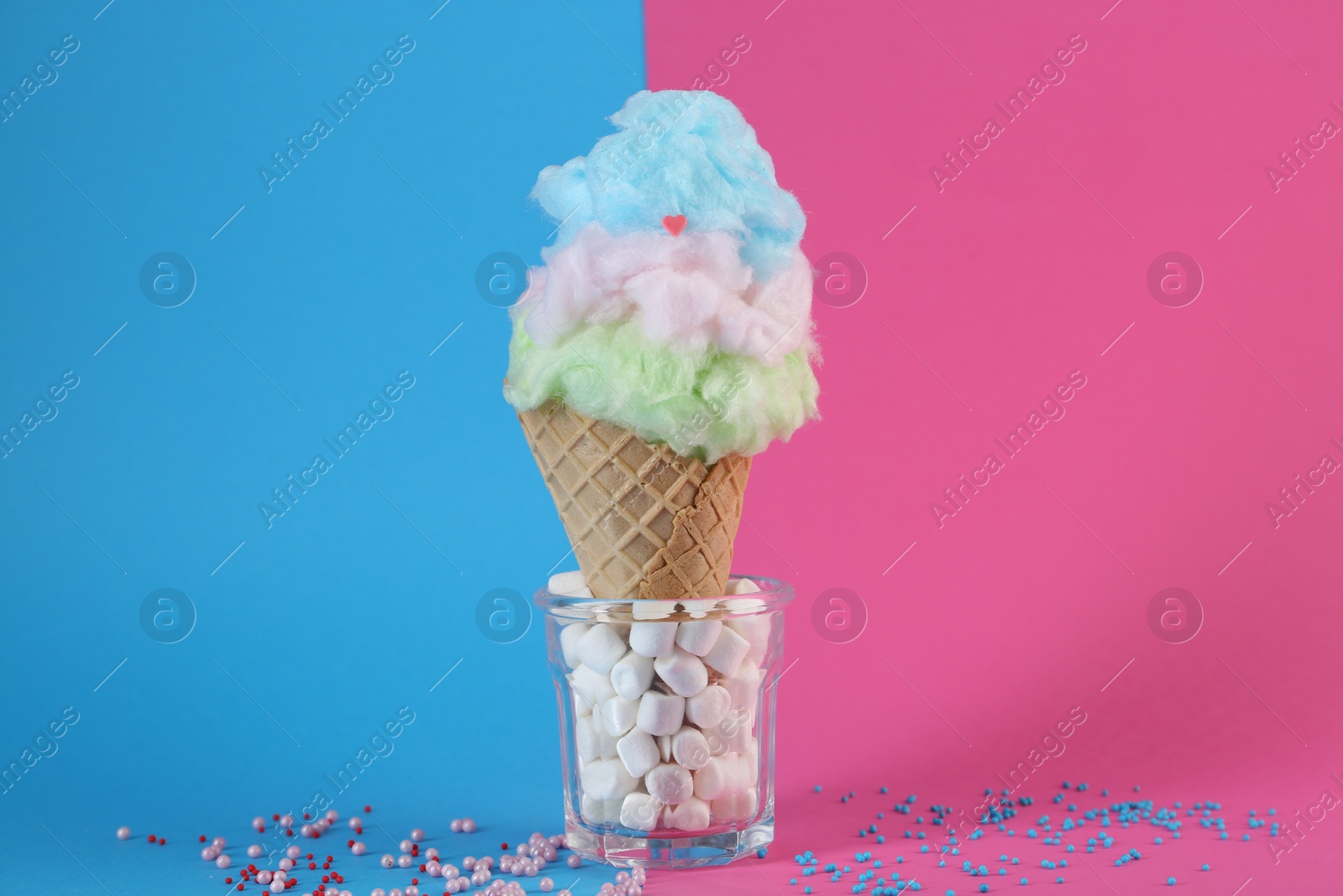 Photo of Sweet cotton candy in waffle cone on color background