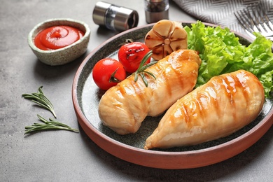 Photo of Plate with grilled chicken breasts and garnish served on table