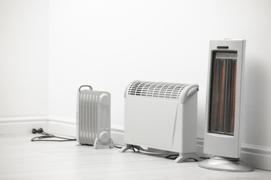 Photo of Different electric heaters near white wall indoors