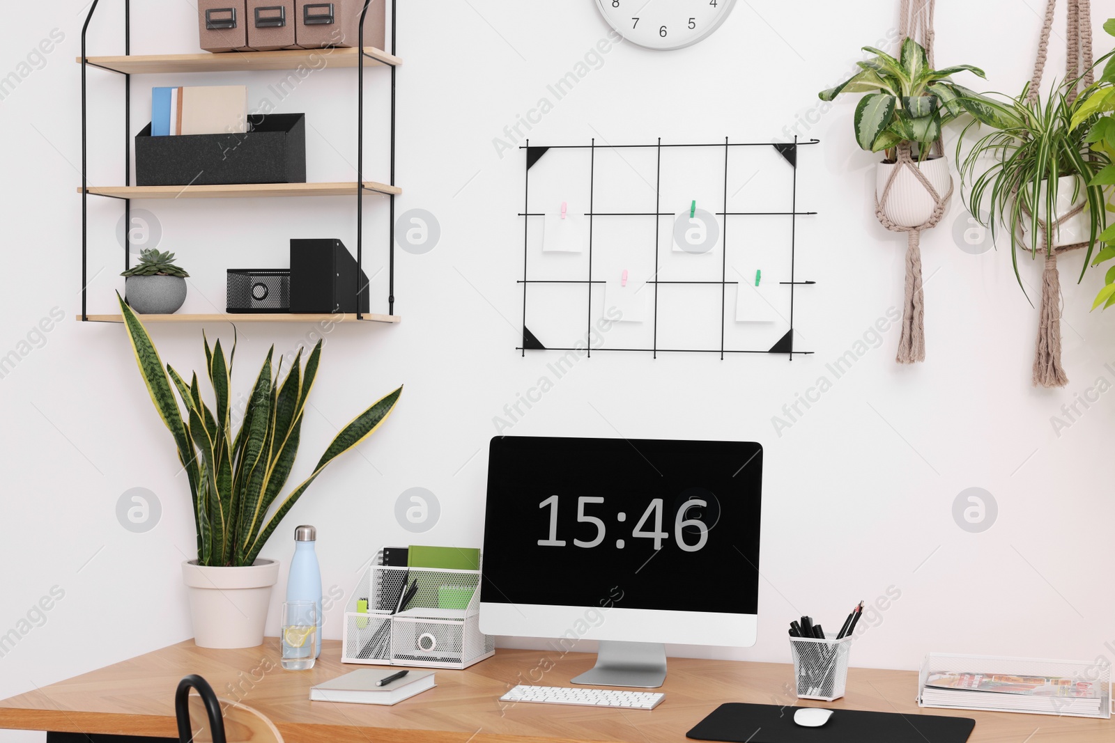 Photo of Cozy workplace with computer, modern furniture and houseplants at home