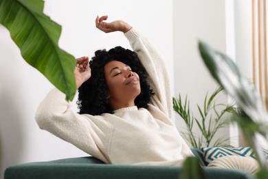 Photo of Woman relaxing on sofa near beautiful houseplants at home