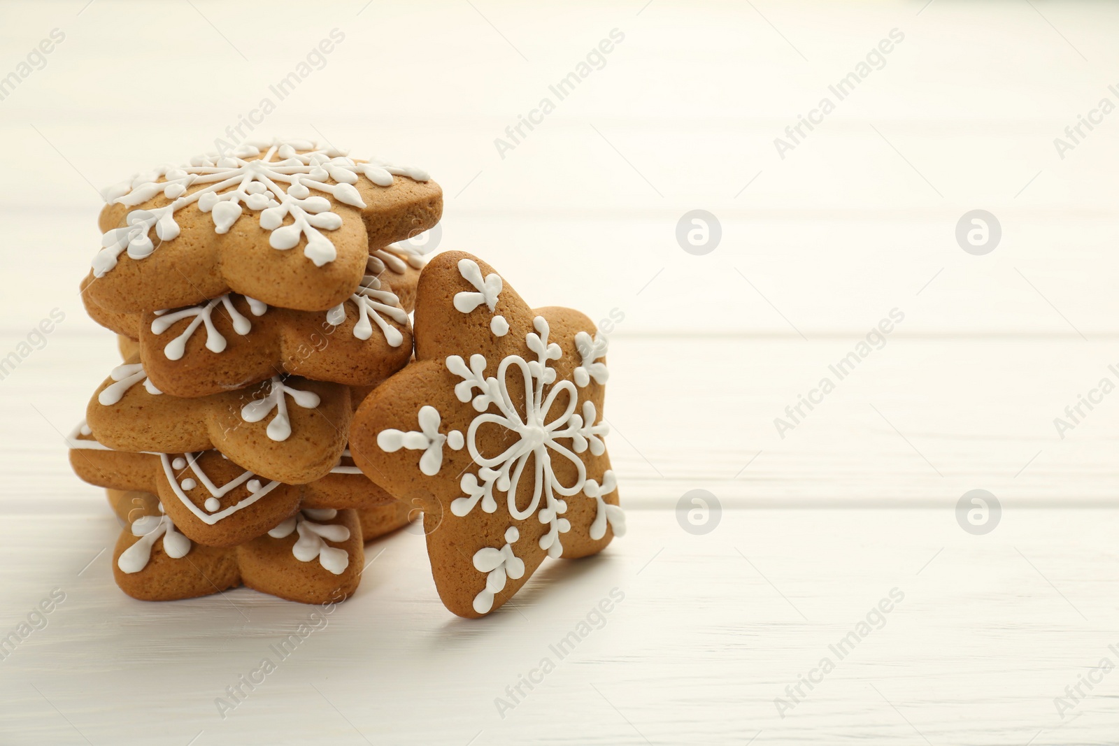 Photo of Tasty Christmas cookies with icing on white wooden table. Space for text